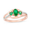 Thumbnail Image 0 of Oval Lab-Created Emerald and 1/20 CT. T.W. Diamond Three Stone Bypass Engagement Ring in 10K Rose Gold