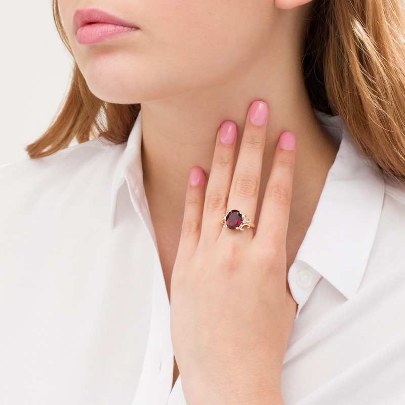 Oval Garnet and 1/20 CT. T.W. Diamond Scroll Frame Ring in 10K Gold