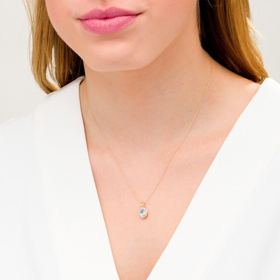 Oval Swiss Blue Topaz and 1/15 CT. T.w. Diamond Frame Pendant in 10K Gold