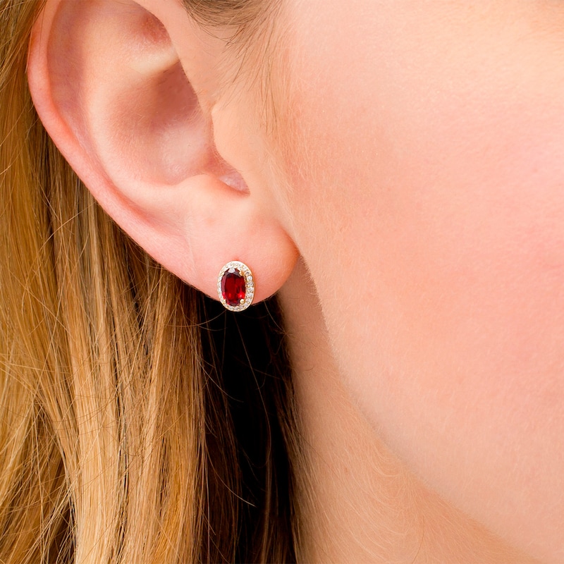 Oval Garnet and 1/10 CT. T.W. Diamond Frame Stud Earrings in 10K Gold