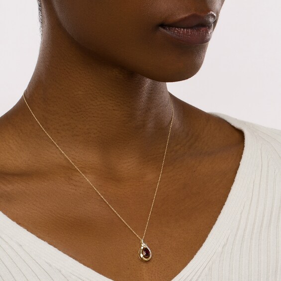 Pear-Shaped Garnet and 1/20 CT. T.w. Diamond Open Frame Ribbon Wrapped Teardrop Pendant in 10K Gold